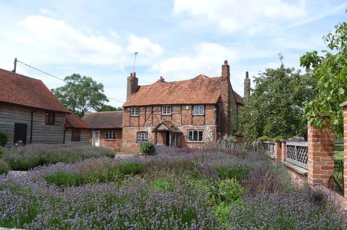 Lavender and perennials in front of a red-brick farmhouse